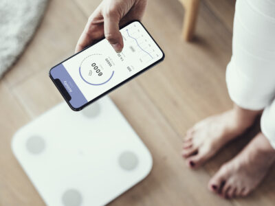 Отслабване за всяка възраст - Body Modulator - woman using health tracking her phone by weighing scale innovative technology